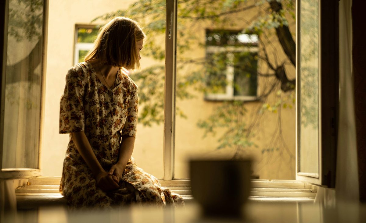 Eine Frau sitzt am offenen Fenster und schaut nach unten